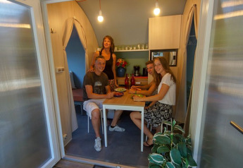 Vier Personen sitzen gemeinsam in einem Safari-Zelt Le Petit Chateau bei La Draille, Frankreich, beim Essen.