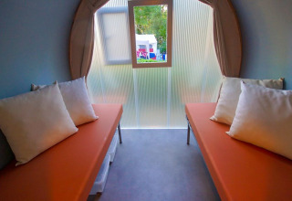 Innenaufnahme eines Safari-Zeltes mit zwei Betten, orange Matratzen und Kissen bei La Draille in Frankreich.