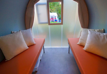 Innenaufnahme eines Safari-Zeltes mit zwei Betten, orange Matratzen und Kissen bei La Draille in Frankreich.