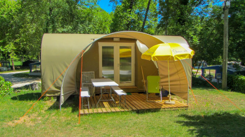 Tienda safari Le Petit Chateau en La Draille, Francia, con terraza de madera, sillas y sombrilla amarilla.