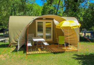 Tienda safari Le Petit Chateau en La Draille, Francia, con terraza de madera, sillas y sombrilla amarilla.