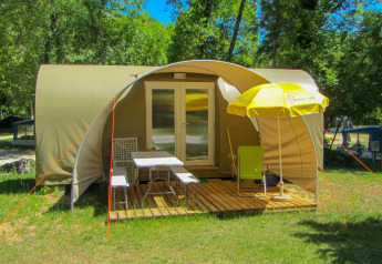 Safaritent Le Petit Chateau aan La Draille in Frankrijk met houten vlonder, stoelen en gele parasol.