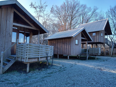Cabañas de madera en River Cottage, Camping de Koeksebelt, Países Bajos, con suelo cubierto de escarcha.