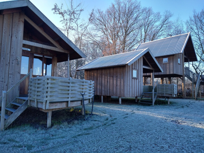 Cabañas de madera en River Cottage, Camping de Koeksebelt, Países Bajos, con suelo cubierto de escarcha.