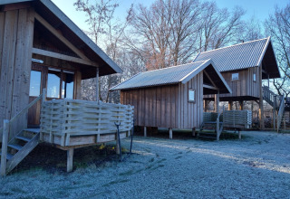 Cabañas de madera en River Cottage, Camping de Koeksebelt, Países Bajos, con suelo cubierto de escarcha.