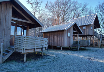 Cabañas de madera en River Cottage, Camping de Koeksebelt, Países Bajos, con suelo cubierto de escarcha.