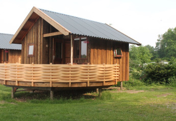 River Cottage auf Camping de Koeksebelt in den Niederlanden, eine urige Holzhütte mit Veranda im Grünen.