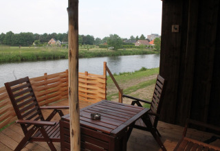 Vista desde River Cottage en Camping de Koeksebelt, Países Bajos, con terraza de madera frente al río.