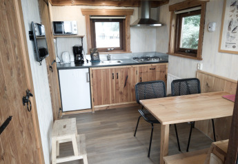 Accogliente cucina e zona pranzo in River Cottage al Camping de Koeksebelt, Paesi Bassi, con interni in legno.