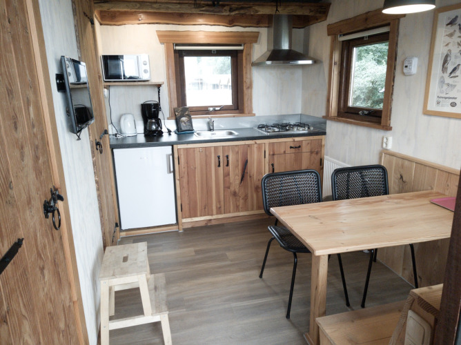 Acogedora cocina y comedor en la River Cottage de Camping de Koeksebelt, Países Bajos, con interior de madera.