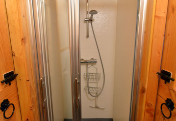 Douche in River Cottage bij Camping de Koeksebelt, Nederland, met glazen deuren en moderne douchekop.