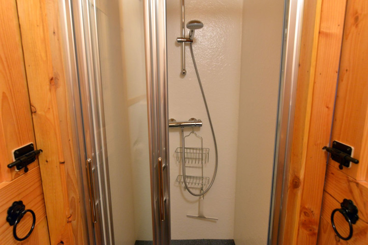 Ducha en River Cottage, Camping de Koeksebelt, Países Bajos, con mamparas de cristal y regadera moderna.
