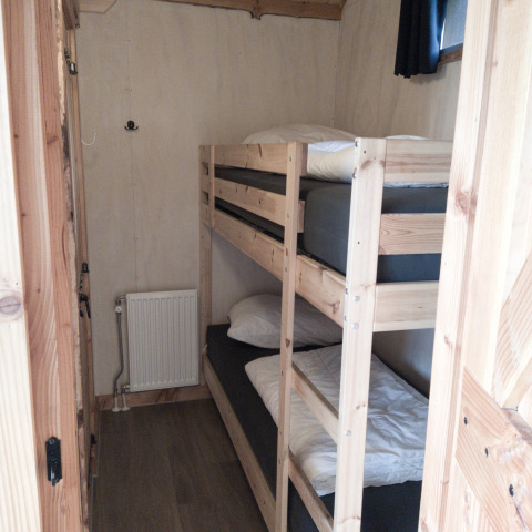 Petite chambre au River Cottage du Camping de Koeksebelt, Pays-Bas, avec lits superposés et décor en bois.