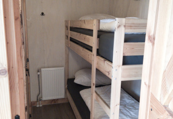 Kleine kamer bij River Cottage in Camping de Koeksebelt, Nederland, met houten stapelbedden en gezellige sfeer.