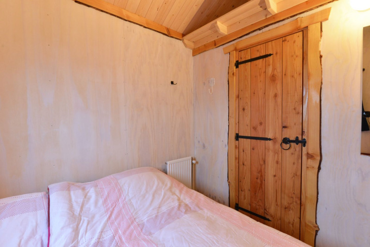 Dormitorio en River Cottage en Camping de Koeksebelt, Países Bajos, con puerta de madera y cama.