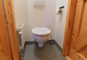 Bagno compatto con WC a parete, porta in legno e radiatore a River Cottage, Camping de Koeksebelt.