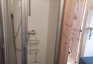 Douche compacte avec porte vitrée et entourage en bois, prise à River Cottage, Camping de Koeksebelt, Pays-Bas.