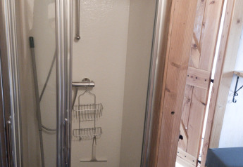 Piccola doccia con porta in vetro e struttura in legno a River Cottage, Camping de Koeksebelt nei Paesi Bassi.
