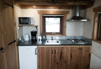 Compacte keuken van River Cottage bij Camping de Koeksebelt, met houten kasten en gasfornuis.