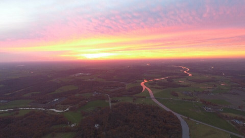 Vista aérea del atardecer sobre River Cottage en Camping de Koeksebelt, Países Bajos, con río serpenteante.