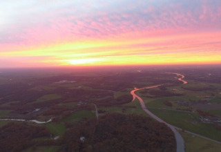 Vue aérienne du coucher de soleil sur River Cottage au Camping de Koeksebelt aux Pays-Bas, avec rivière.