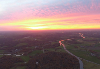 Vue aérienne du coucher de soleil sur River Cottage au Camping de Koeksebelt aux Pays-Bas, avec rivière.
