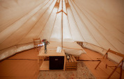 Interior de una confortable tienda tipi con cama doble y sillas en Duo Tipi de RØSTIG, Países Bajos