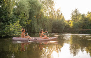 Due donne su un kayak remano su un lago circondato da alberi presso una sistemazione glamping.