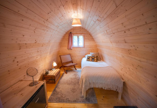 Habitación de cápsula Solo en RØSTIG, Países Bajos, con cama individual, decoración de madera y ventana.