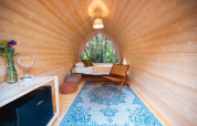 Premium Solo Panoroma Pod en RØSTIG, Países Bajos, con interior de madera y vista al bosque.