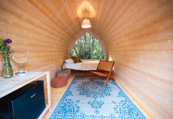 Premium Solo Panoroma Pod presso RØSTIG nei Paesi Bassi con interno in legno e vista sul bosco.