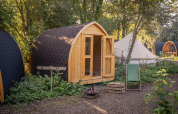 Premium - Solo Panorama Pod en RØSTIG, Países Bajos, con cabaña de madera, tienda y naturaleza verde.