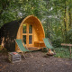 Duo Pod bij RØSTIG Nederland: houten hut, twee groene stoelen, vuurschaal en bosrijke omgeving.
