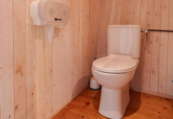 Toilet i træbeklædt badeværelse på Luxe & Lazy Lodge, RØSTIG Dorst, Holland, set fra siden.