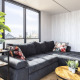 Moderne woonkamer op woonboot 'Iere Fügel', grote ramen, grijze zetel en planten, Friesland, Nederland.