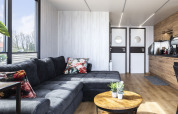 Modernes Wohnzimmer auf einem Hausboot mit grauem Sofa, runden Türen und Küchenzeile in Friesland.