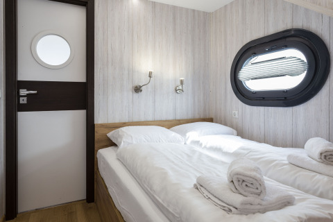 Tweepersoons slaapkamer met maritieme accenten en patrijspoort op Houseboat 'Iere Fügel', Friesland, Nederland.