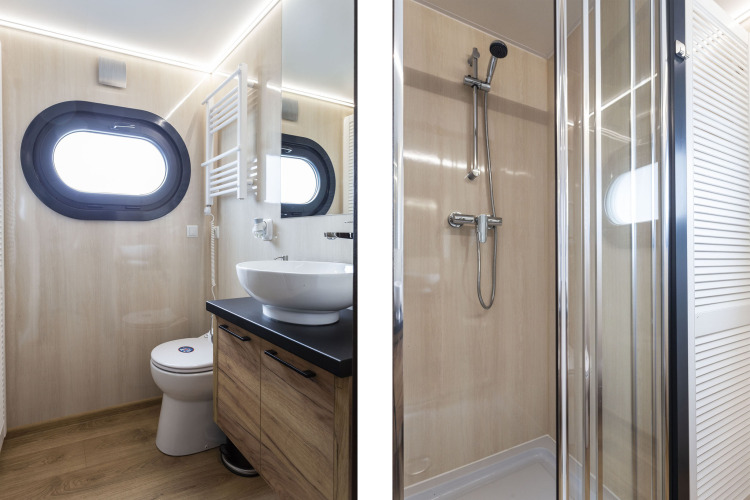 Baño moderno en la casa flotante 'Iere Fügel' con ventana redonda, lavabo, inodoro y ducha en Frisia.