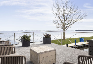 Vista desde Houseboat 'Iere Fügel' en Friesland, Países Bajos, con terraza, lago y árbol al fondo.