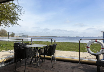 Udsigt fra husbåd Houseboat 'Iere Fügel' med terrasse, bord, stole og udsigt over vandet i Friesland.