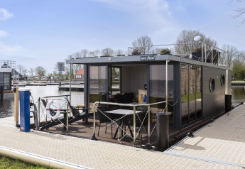 Moderne husbåd kaldet 'Iere Fügel' fortøjet ved en havn i Friesland, Holland på en solskinsdag.