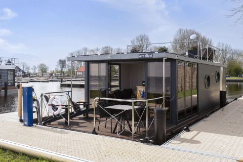 Moderne husbåd kaldet 'Iere Fügel' fortøjet ved en havn i Friesland, Holland på en solskinsdag.