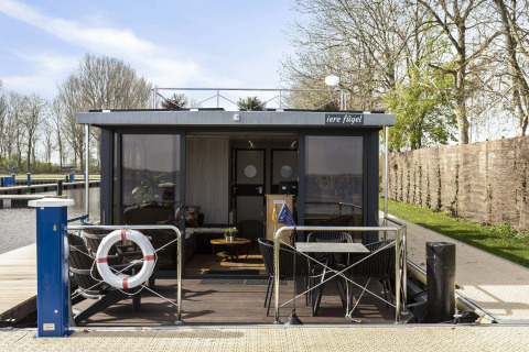 Casa flotante 'Iere Fügel' en Welcome In - Friesland, Países Bajos, con terraza y vistas al canal.