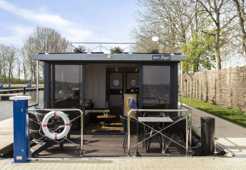 Casa flotante 'Iere Fügel' en Welcome In - Friesland, Países Bajos, con terraza y vistas al canal.