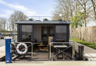 Hausboot 'Iere Fügel' bei Welcome In - Friesland, Niederlande, mit moderner Terrasse und Wasserblick.