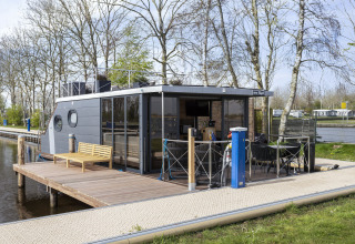 Péniche moderne 'Iere Fügel' à Welcome In - Friesland, Pays-Bas, amarrée à un quai en bois arboré.