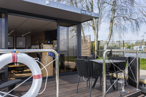 Terraza exterior en la casa flotante 'Iere Fügel' en Welcome In - Friesland, Países Bajos, con asientos modernos.