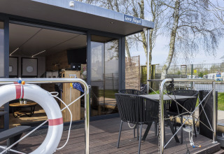 Terraza exterior en la casa flotante 'Iere Fügel' en Welcome In - Friesland, Países Bajos, con asientos modernos.