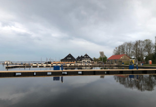 Vista de un puerto deportivo con casas flotantes en Welcome In - Friesland, Países Bajos, bajo cielo nublado.