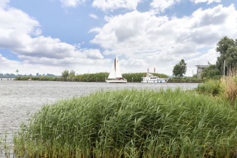 Vista al río con veleros y casa flotante cerca de Houseboat 'Iere Fügel' en Friesland, Países Bajos.